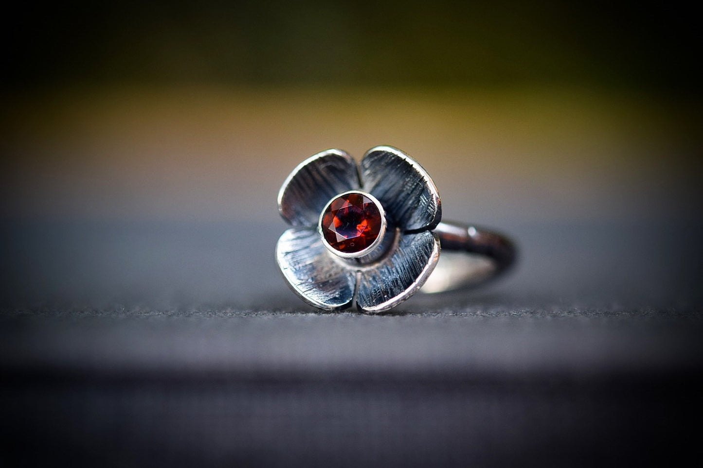 Oxidized sterling silver flower ring with red/ orange fire citrine in center of 4 petal textured flower.